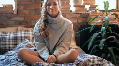 Evde yatakta kameraya poz veren bir kadın. 