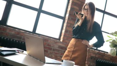 İş kadını ofiste akıllı telefondan konuşuyor.