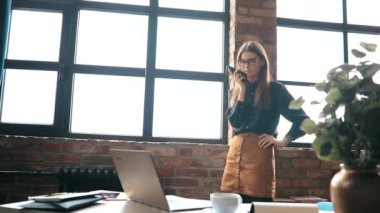 İş kadını ofiste akıllı telefondan konuşuyor.