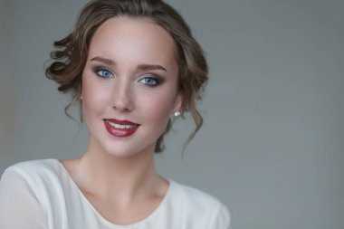 Gri arka planda makyajlı hoş bir genç kadın.