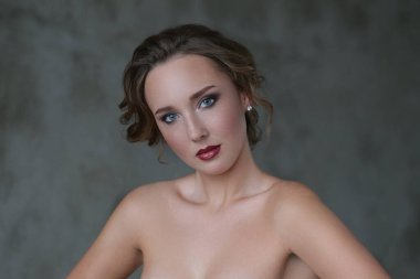 Gri arka planda makyajlı hoş bir genç kadın.