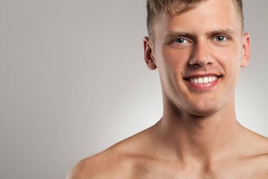 Gri arka planda yakışıklı, çıplak, beyaz bir adamın portresi.