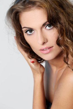 kıvırcık saçlı ve hafif bir arka plan üzerinde poz çıplak omuzlarına güzel esmer bir kadın portresi