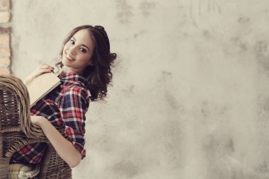 Evde elinde kitapla tatlı bir kadın var.