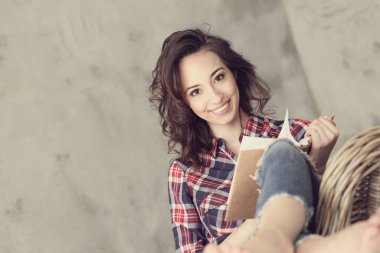 Evde elinde kitapla tatlı bir kadın var.