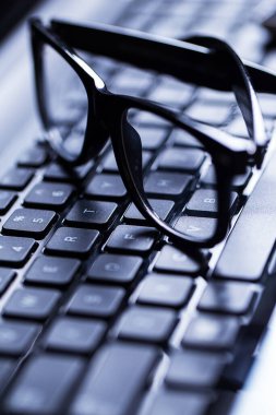 Üzerinde gözlük olan parlak bir dizüstü bilgisayarın yakın plan fotoğrafı.