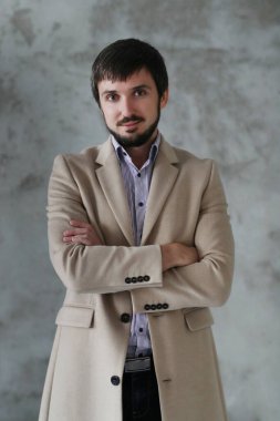 Palto giyen yakışıklı adamın stüdyo portresi.