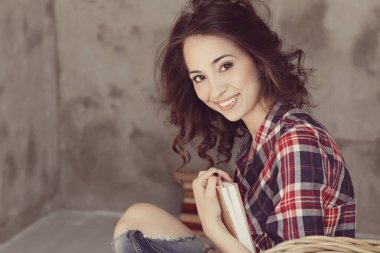 Evde elinde kitapla tatlı bir kadın var.