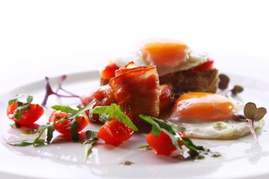 Çırpılmış yumurta, domuz pastırması ve yeşil bir tabakta servis edilir.