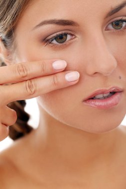 Örgü örmüş güzel bir kızın portresi. Kendine dokunuyor ve beyaz bir arka planda poz veriyor.