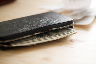 Tahta masada üzerinde para olan deri cüzdan ve bazı çekler.