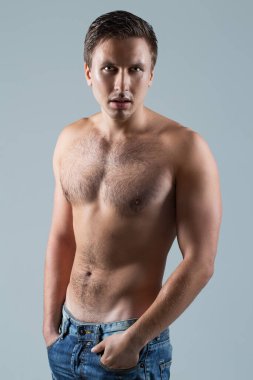 Açık mavi bir arkaplanda çıplak poz veren yakışıklı bir adamın portresi.