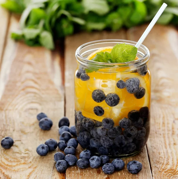 Çilek ve limonla dolu bir kavanoz. Tahta bir yüzey üzerinde kamışla.