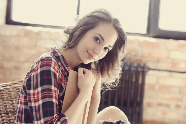 Evde elinde kitapla tatlı bir kadın var.