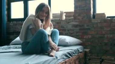 Evdeki yatakta kameraya poz veren bir kadın. 