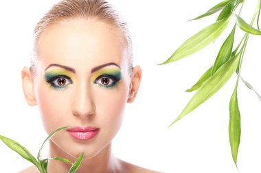 Sanatsal makyajlı ve bambu yapraklı güzel bir sarışın.