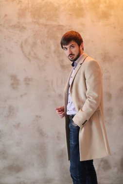 Palto giyen yakışıklı adamın stüdyo portresi.