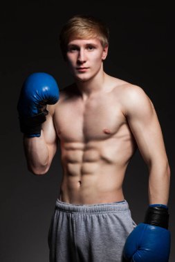 Siyah arka planda mavi eldivenli yakışıklı bir boksör.