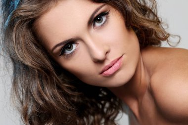 kıvırcık saçlı ve hafif bir arka plan üzerinde poz çıplak omuzlarına güzel esmer bir kadın portresi