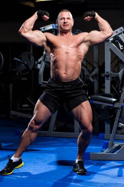 Yakışıklı kaslı adam spor salonunda çalışıyor.