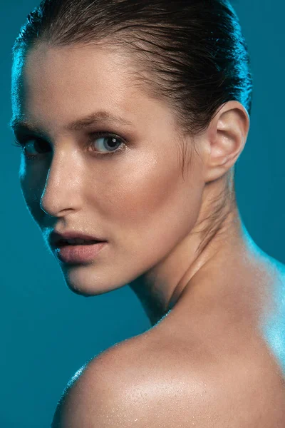 güzel bir kız ıslak deri ile mavi bir arka plan üzerinde poz
