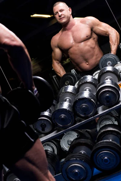 Yakışıklı kaslı adam spor salonunda çalışıyor.