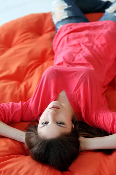 一个性感的年轻女人躺在橙色毯子上做梦 — 图库照片