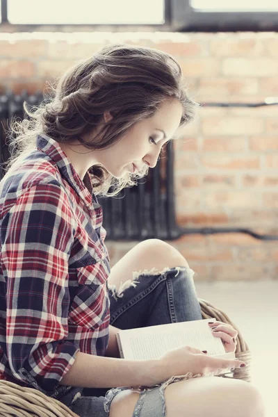 Evde elinde kitapla tatlı bir kadın var.