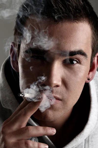フード喫煙タバコの若くてハンサムな男 — ストック写真