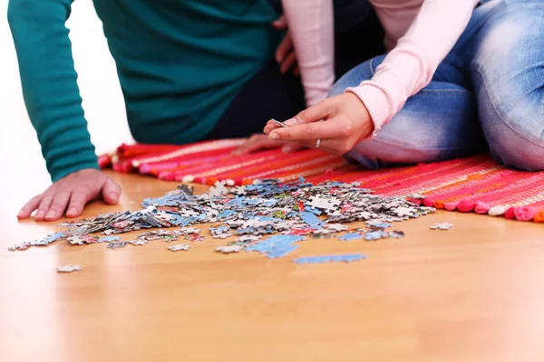 Granny and granddaughter playing puzzle on a floor