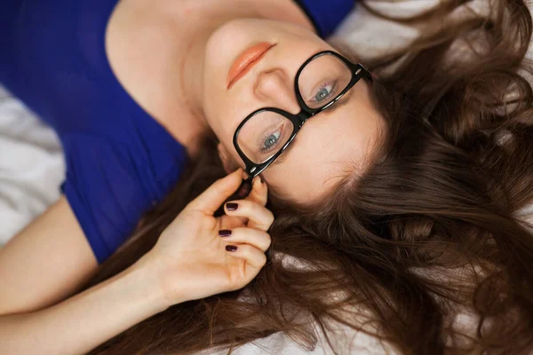 Yatakta poz veren gözlüklü tatlı genç kız. 