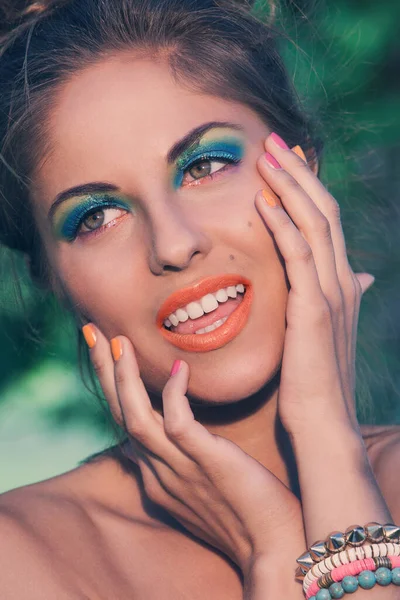 Güzel sanatsal makyaj ve renkli bileziklerle poz veren bir kızın portresi.