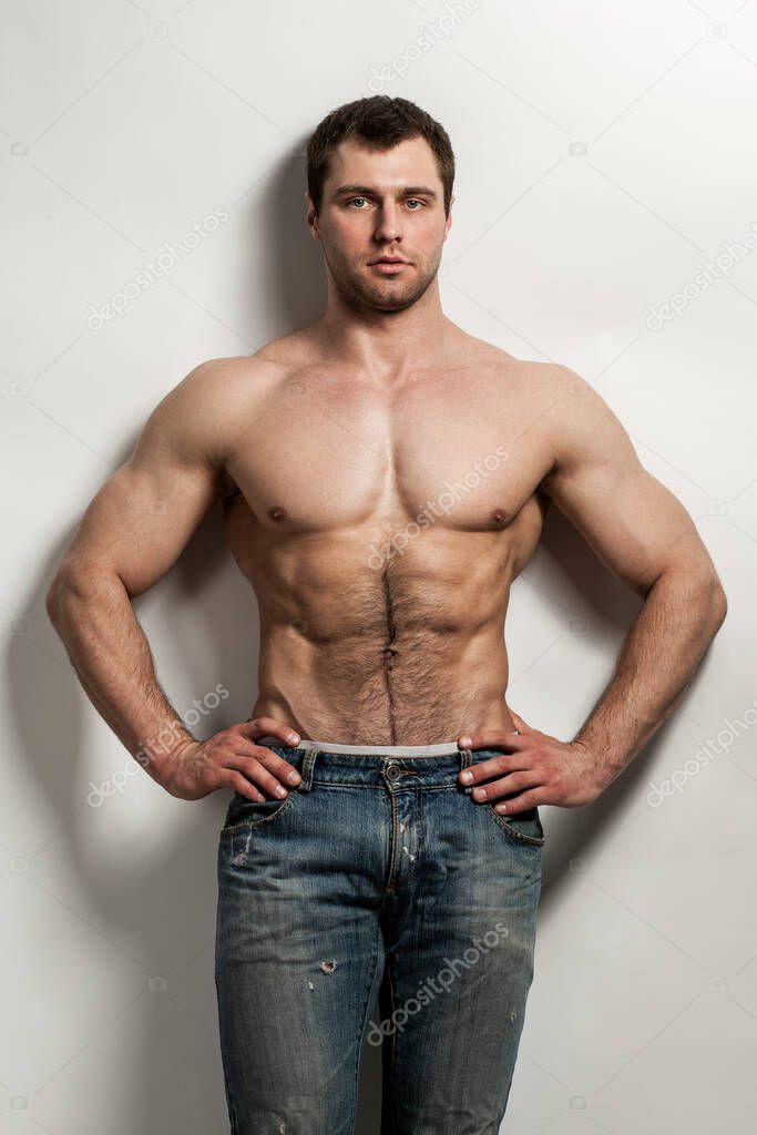 Handsome muscular guy with naked torso isolater over a grey background