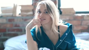 Evdeki yatakta kameraya poz veren bir kadın. 