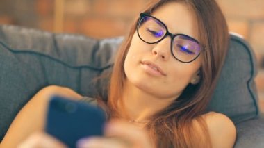 Evde akıllı telefon kullanan genç bir kadın.