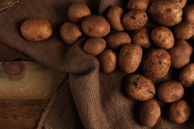 Ahşap masalarda kabuğu soyulmamış taze patates.