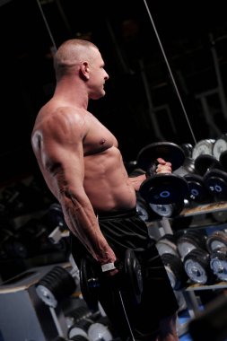 Yakışıklı kaslı adam spor salonunda çalışıyor ve poz veriyor.