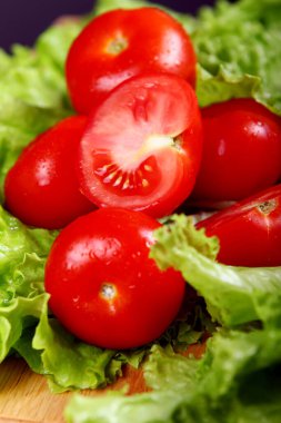 Salata yapraklarının üzerinde duran taze ve ıslak domatesler.