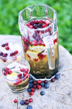 Bir kavanozda canlandırıcı içecek, tahta bir kütükte iki bardak.