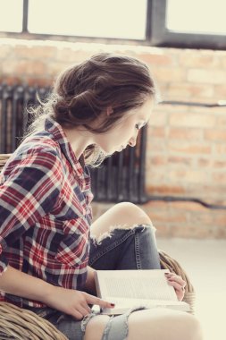 Evde elinde kitapla tatlı bir kadın var.