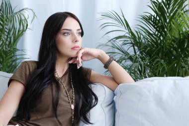 Evdeki kanepede oturan güzel bir kadın.