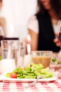 Sağlıklı salata ve kırmızı şarap bir restoranda kare masa örtüsü üzerinde.