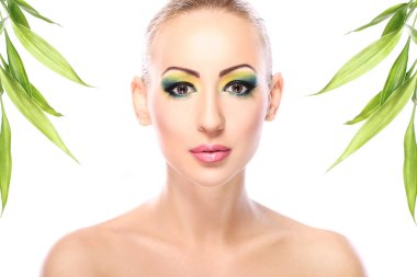 Sanatsal makyajlı ve bambu yapraklı güzel bir sarışın.