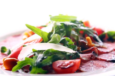 Biftek carpaccio roka ve mantarla servis edilir.