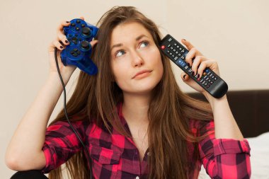 Genç bir kadın TV konsolu ile joystick arasında seçim yapamaz.