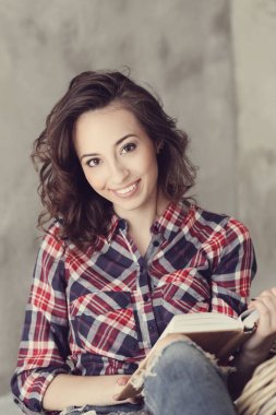 Evde elinde kitapla tatlı bir kadın var.