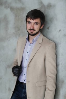 Palto giyen yakışıklı adamın stüdyo portresi.