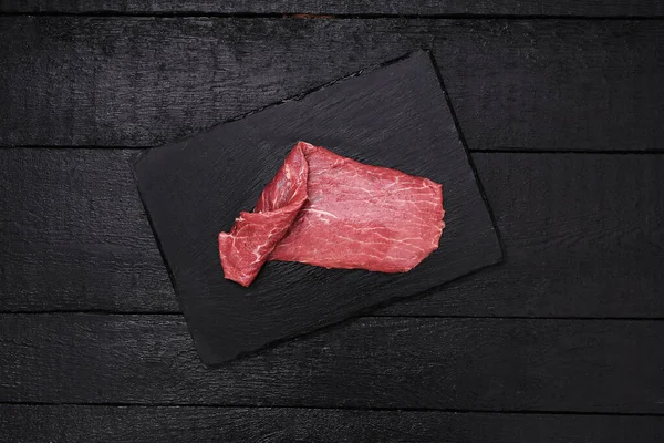 Frisches Fleisch Auf Einem Schwarzen Schneidebrett — Stockfoto