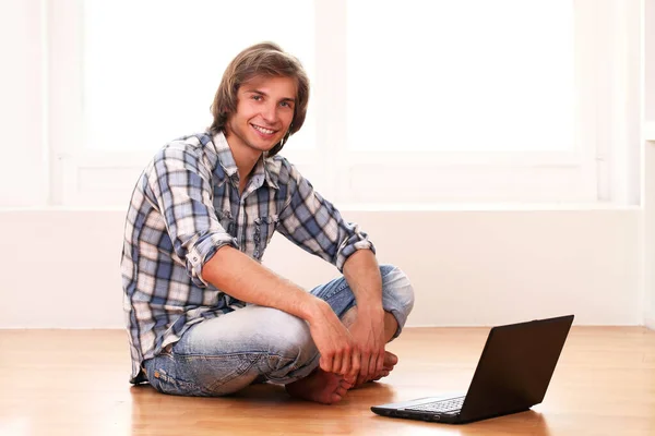 用的笔记本电脑在家里放松的年轻和快乐的家伙 — 图库照片