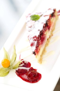 Lezzetli katmanlı meyveli kek ve beyaz tabakta diğer meyveler.